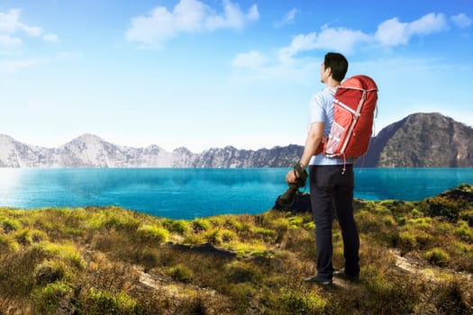 Handsome asian photograper man with backpack and camera on the mountain