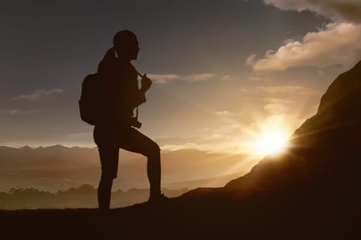 Silhouette of traveler woman hiking the mountain at sunset