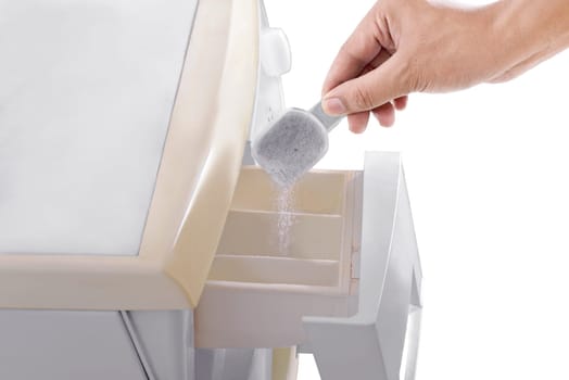 Human hands put the detergent into the washing machine isolated over white background