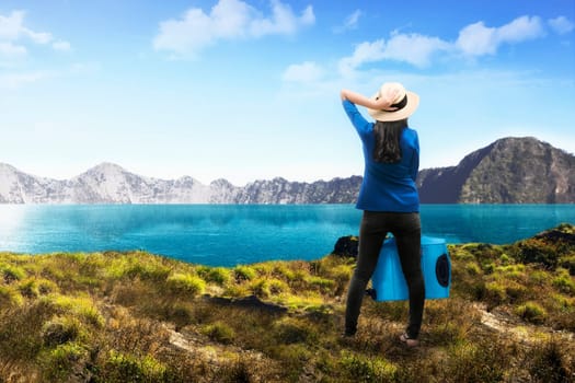 Rear view of asian female tourist with suitcase on the mountain