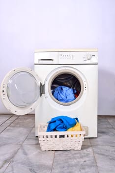 Clothes in basket and washing machine. Home appliance