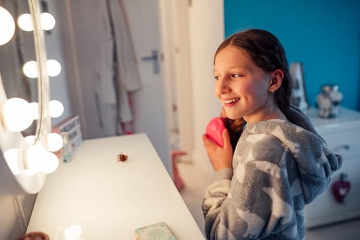 Little girl is brushing her hair at the mirror in her bedroom.