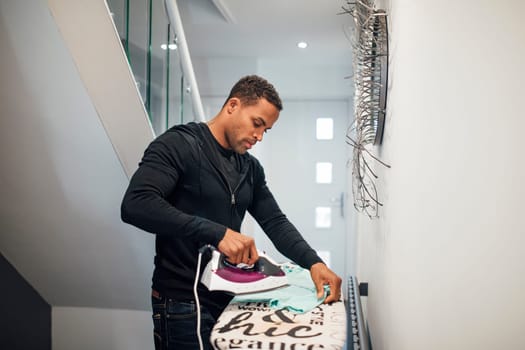 Mid adult man is ironing a school shirt in the hallway at home.