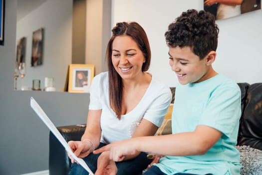 Little boy and his mother are looking at the Father's Day card they have made together at home.