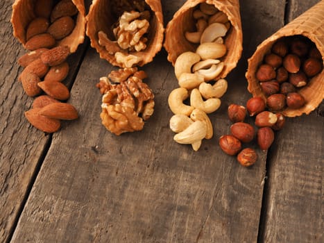 Ice cream cone with organic hazelnuts, almonds, cashews and walnuts on a rustic wooden table