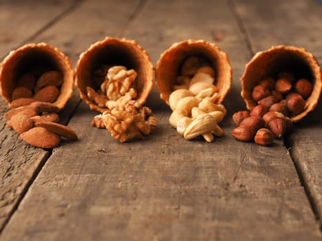 Ice cream cone with organic hazelnuts, cashews, almonds and walnuts on a rustic wooden table
