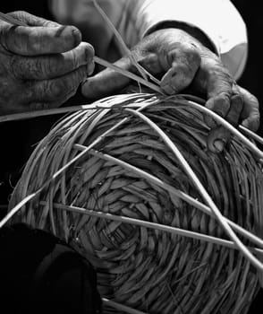 Detail of a man's hands in monochrome making a wicker basket