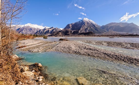 Mountain landscape,with river rocks and waterfall against blue sky.