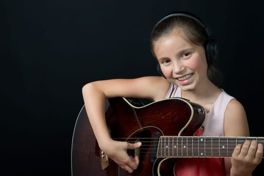 a pretty little girl whit headphones playing guitar
