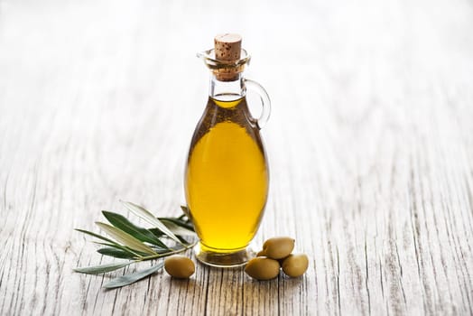 Olive oil with olive branch on wooden table