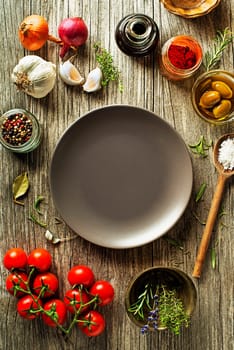 Fresh ingredients and spices on wooden background. Healthy cooking concept. Background with empty plate and space for text recipe or menu