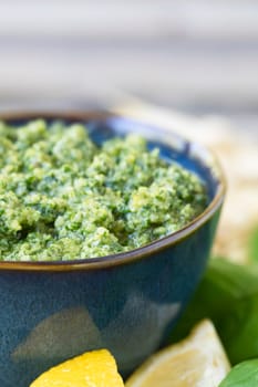 Close up of bowl of fresh pesto with lemons and some copy space at top