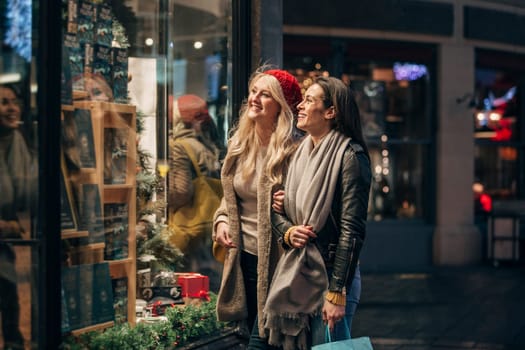 Side view of two mid adult women looking in a store window while doing some christmas shopping.