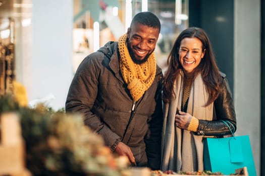 Front view of a couple standing at a christmas market stall deciding on what wreath they should buy.