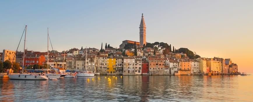 Colorful sunset of Rovinj town, Croatian fishing port on the west coast of the Istrian peninsula. Colorful evening seascape of Adriatic Sea. Traveling concept.