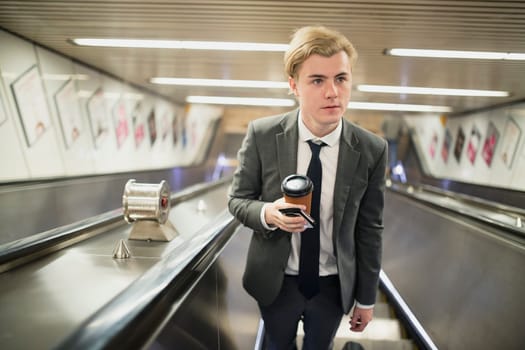 Young businessman moving up an escalator on his morning commute to work.