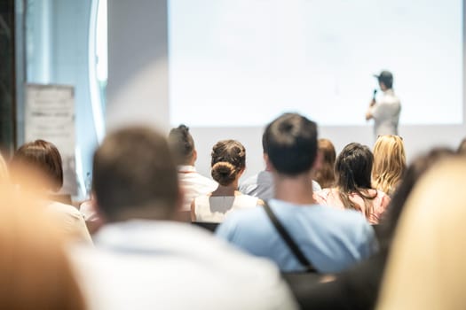 Speaker giving a talk in conference hall at business event. Audience at the conference hall. Business and Entrepreneurship concept. Focus on unrecognizable people in audience.