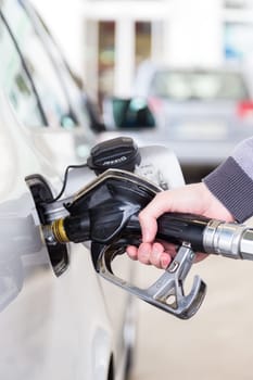 Pumping gas at gas pump. Closeup of man pumping gasoline fuel in car at gas station.