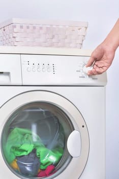 Male hand setting the program on washing machine. Home appliance