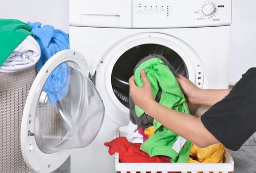 Male loading dirty clothes from basket to washing machine for washed. Home appliance