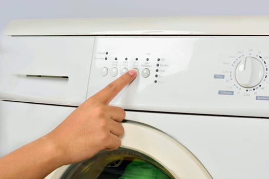 Closeup of hand push the button on washing machine isolated over white background