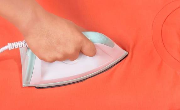 Man hand ironing colored clothes on ironing board