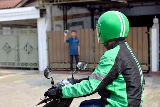Motorcycle taxi man approached the passenger in front of the home