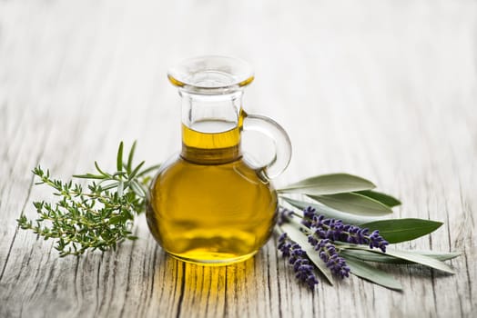 Olive oil with fresh herbs on wooden background