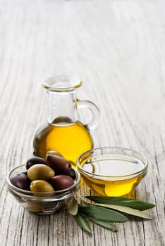 Olive oil with olive branch on wooden table