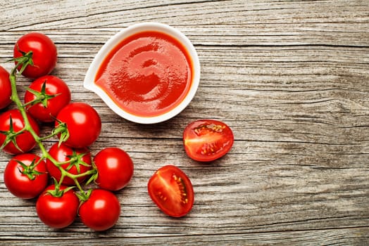 Fresh cherry tomato sauce or ketchup on rustic wooden background