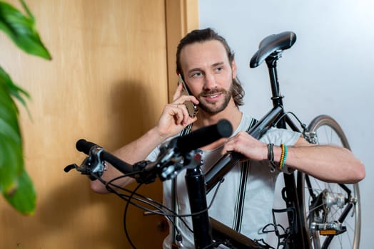 young bearded man calling with bike on the shoulder
