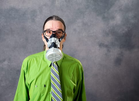 young business man in green shirt with gas mask in front of gray background