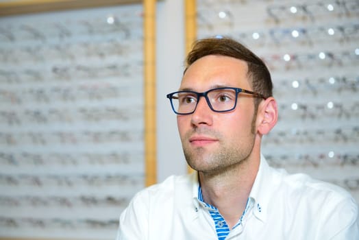 in optician shop- young dark haired man with new glasses