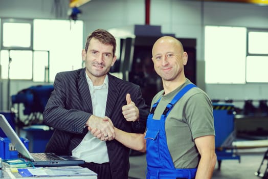 in the factory- young boss and worker with thumb up