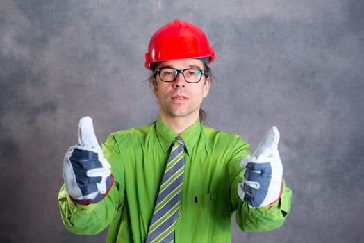 young architect in green shirt with red helmet and thumb up