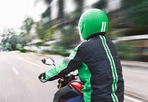 Rear view of motorcycle taxi driver with black and green unifrom on the street