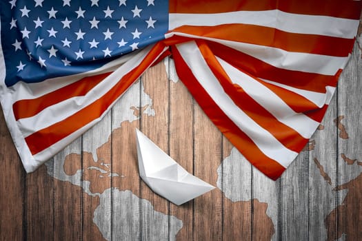 American flags and paper boat with wooden background. Columbus day concept