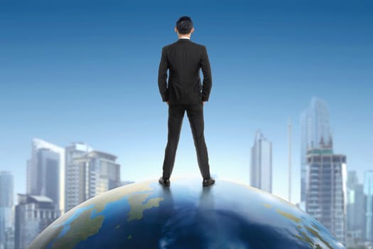 Rear view of asian businessman standing on earth and looking at cityscape view with blue sky background