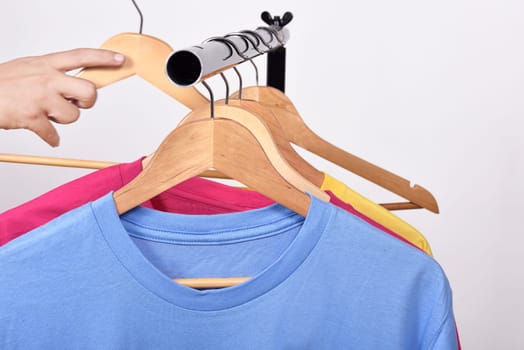 Male hand taking a hanger for clothes from shelf isolated over white background