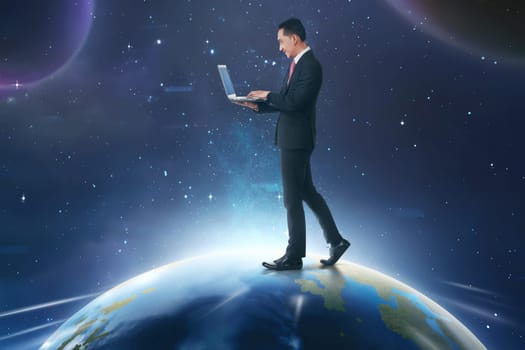 Asian businessman using laptop while walking on earth with outer space background