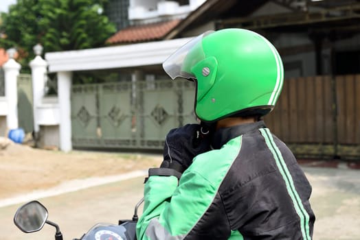Portrait of motorcycle taxi driver wearing helmet before driving on the city