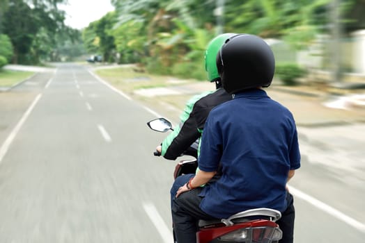 Portrait of motorcycle taxi driver delivering the passenger to his destination on the city