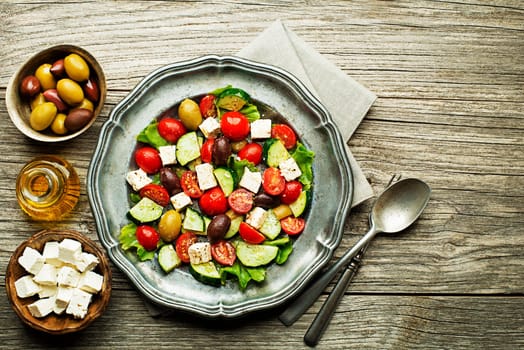 Salad with feta cheese and fresh vegetables on wooden background. Greek salad.