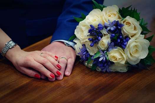 Hands with rings and bouquet. Concept for wedding and new marriage celebrations.