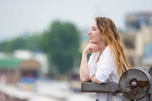A young girl looks into the distance leaning on the old fence