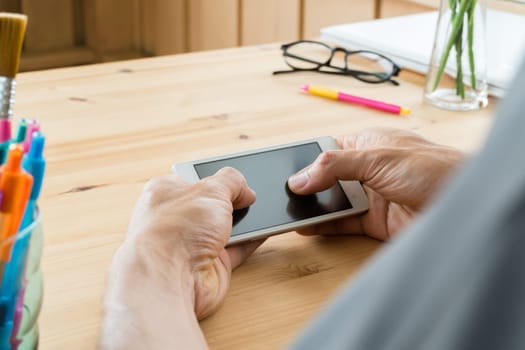 Gray shirt businessman chat smartphone or mobile phone in home office. Smartphone or mobile phone and pen and laptop and eyeglasses. Social or internet and technology communication concept