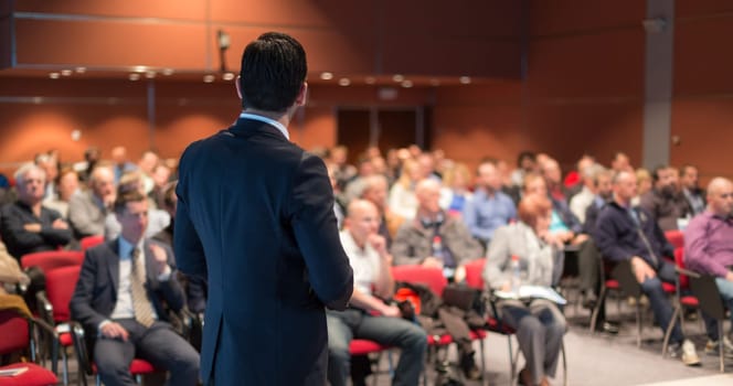 Speaker giving a talk on corporate business conference. Unrecognizable people in audience at conference hall. Business and Entrepreneurship event.