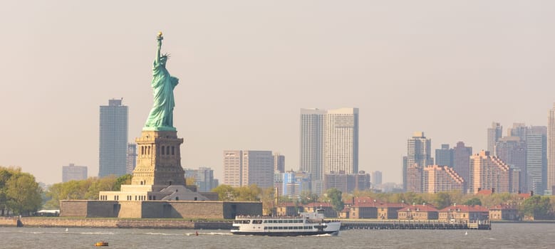 Statue of Liberty with Liberty State Park and Jersey City skyscrapers in background, USA.