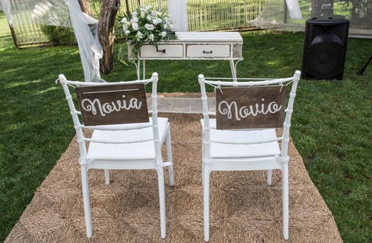 Chairs for bride and groom at altar. Spanish sign Novia y Novio