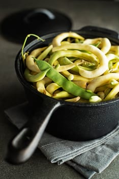Cooked fresh green and yellow beans in black pan